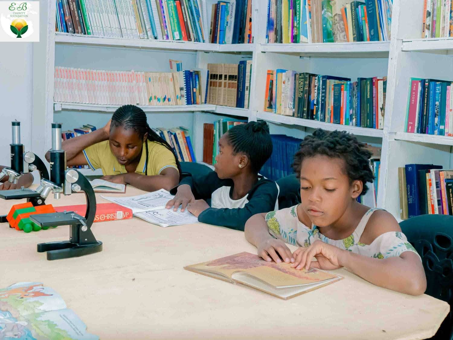 Students studying at a table with books and a microscope